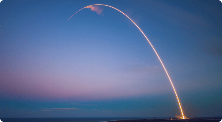 rocket shooting into space at dusk